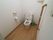 温水洗浄便座が完備されているトイレには、Ｌ字型の手すり、緊急呼び出しブザーが設置されている。清掃用具が置かれている。