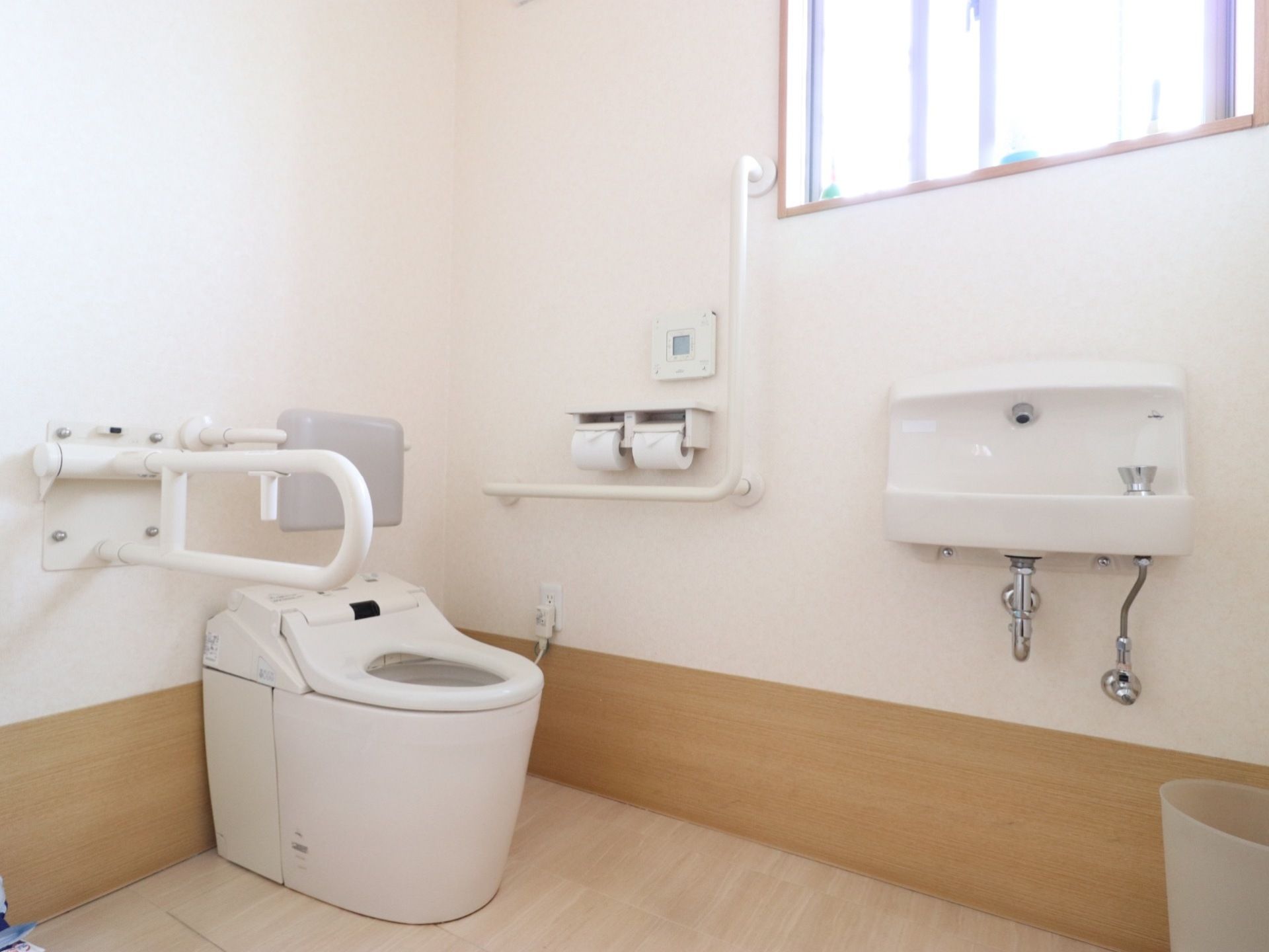 お手洗いには温水洗浄便座のついた洋式便器を備え付けている。また壁には操作パネルがあり、洗面台が取り付けられている。