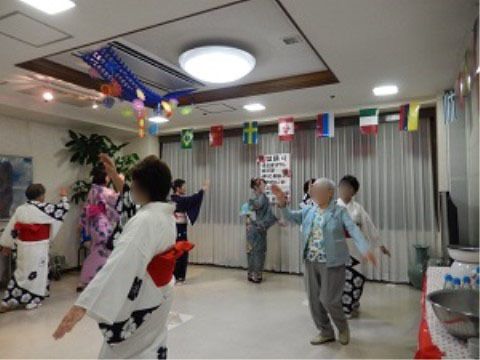 輪になって盆踊りを踊っている入居者様と浴衣を着たスタッフ