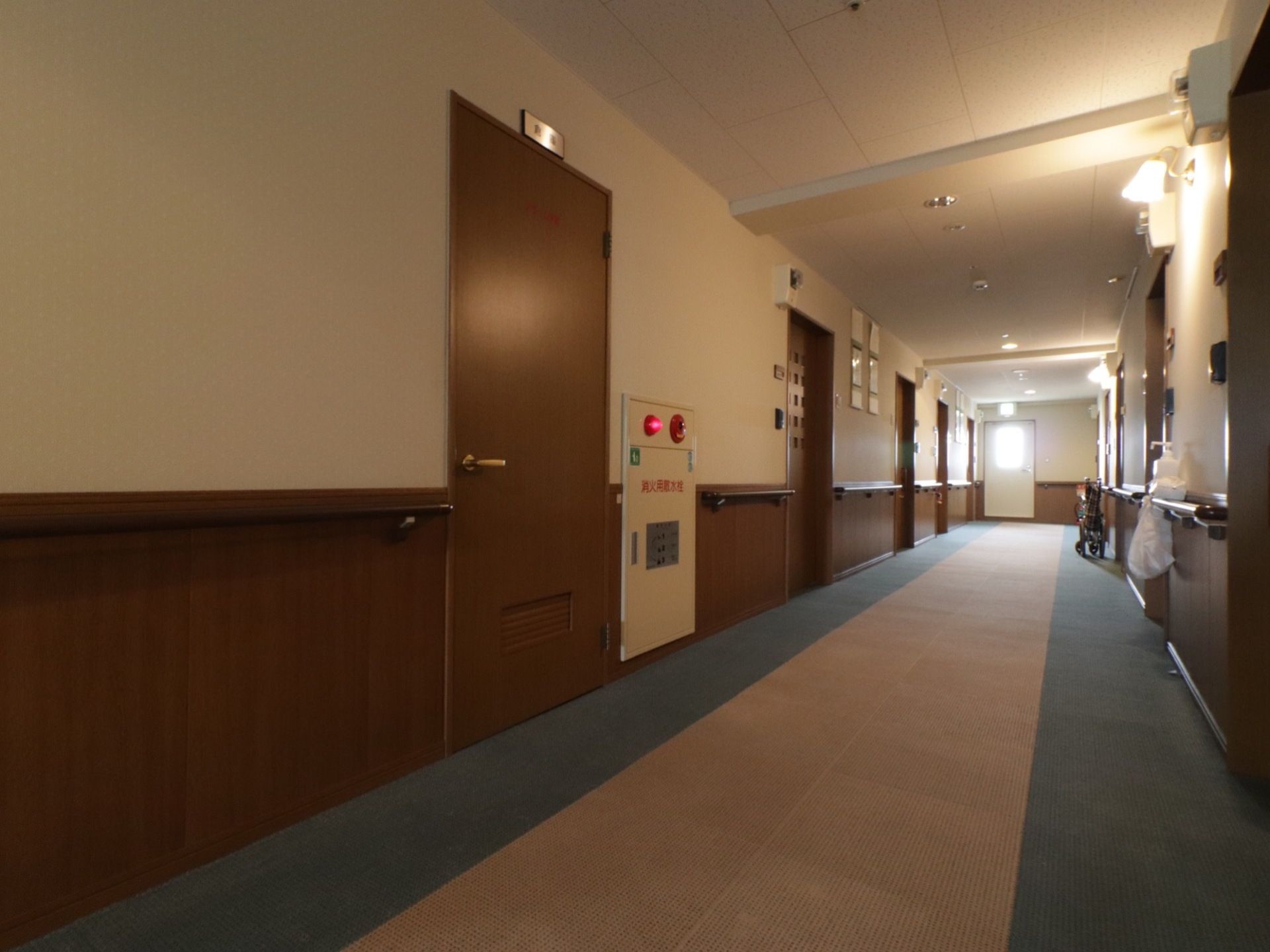 通路幅は広々としている。両側には部屋の扉、手すりが並んでいる。消火用散水栓ボックスが設置されている。