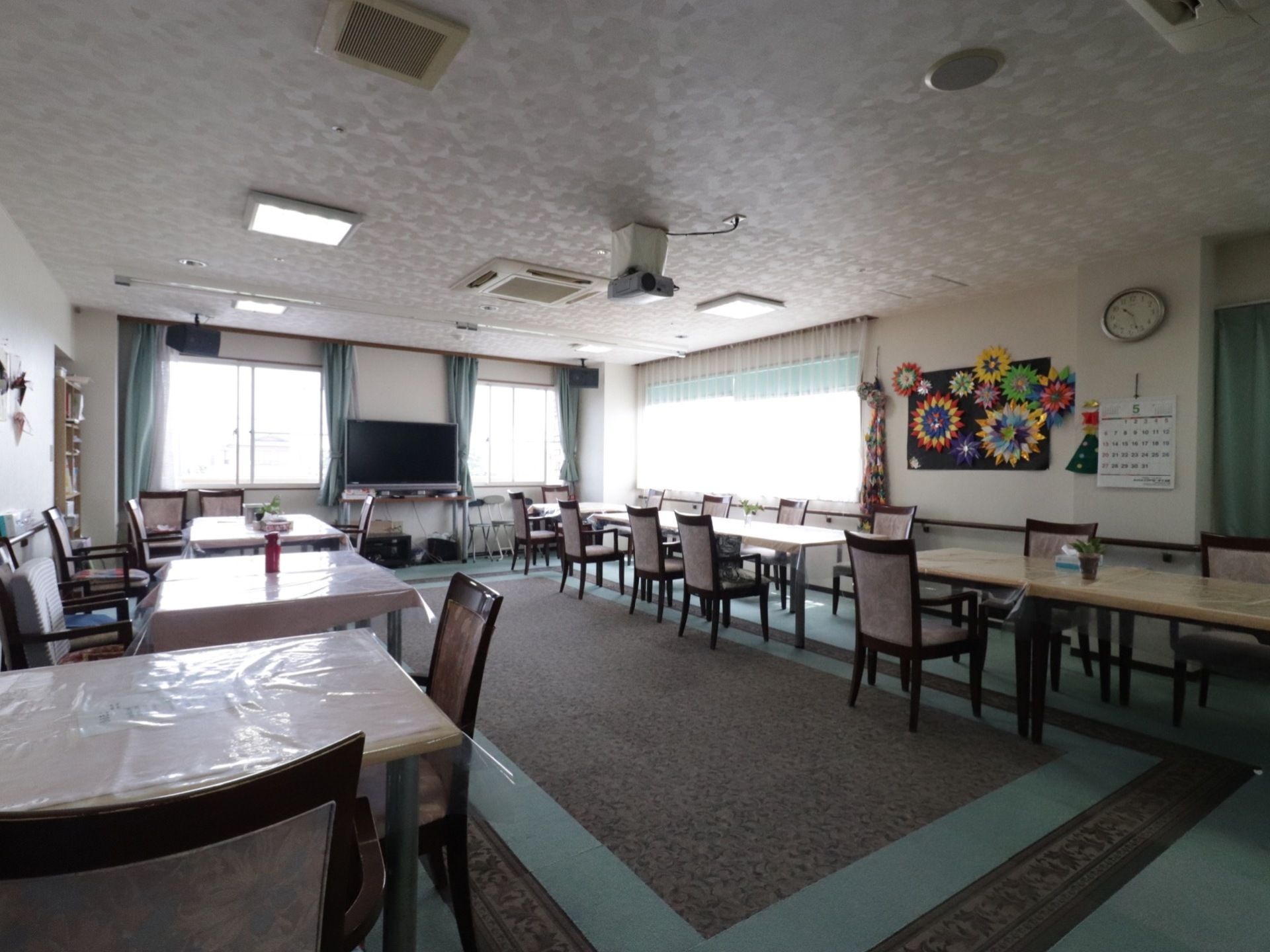 食堂の窓は大きく、昼間は明るい光が入る。壁際には大きな液晶テレビが設置されている。壁には工作作品が掲示されている。