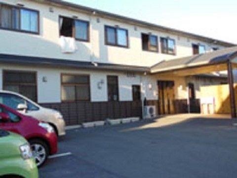 白い壁に濃い茶色の窓枠や屋根が和風の印象の施設外観