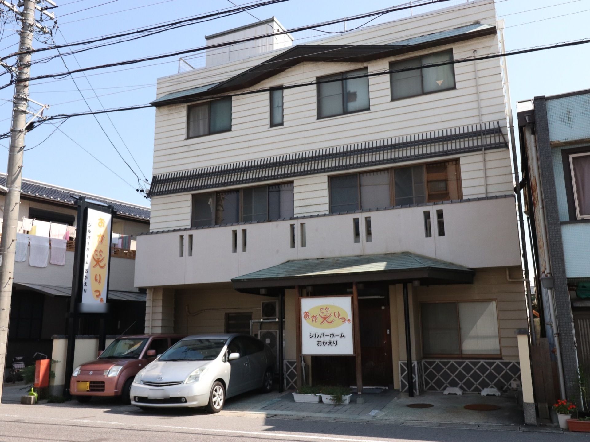 当施設は三階建てであり、各部屋に窓が設置されている。また、玄関前には看板があり、数台分の駐車スペースがある。