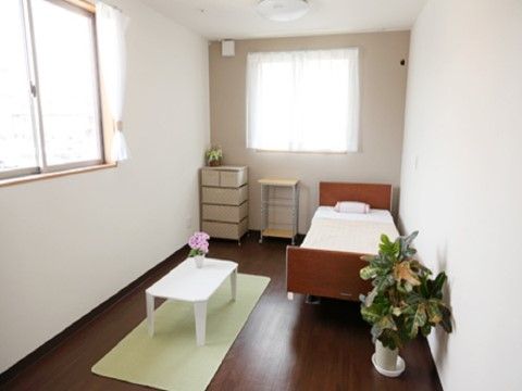 窓が2面に設けられた、白い壁と濃い茶色いの床の角部屋の居室