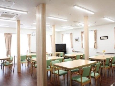 ４人掛けのテーブルと椅子が複数セッティングされている。４本の柱が立っており、部屋の角には大きなテレビが設置されている。