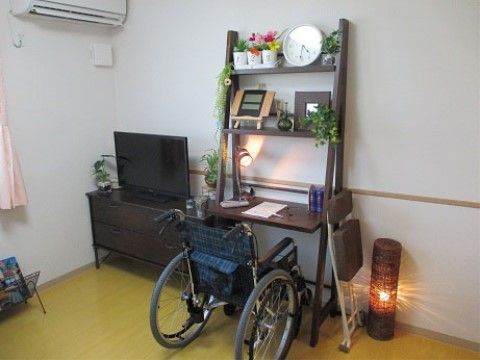 居室に置かれた、車椅子でも作業が可能な棚と一体型のデスク