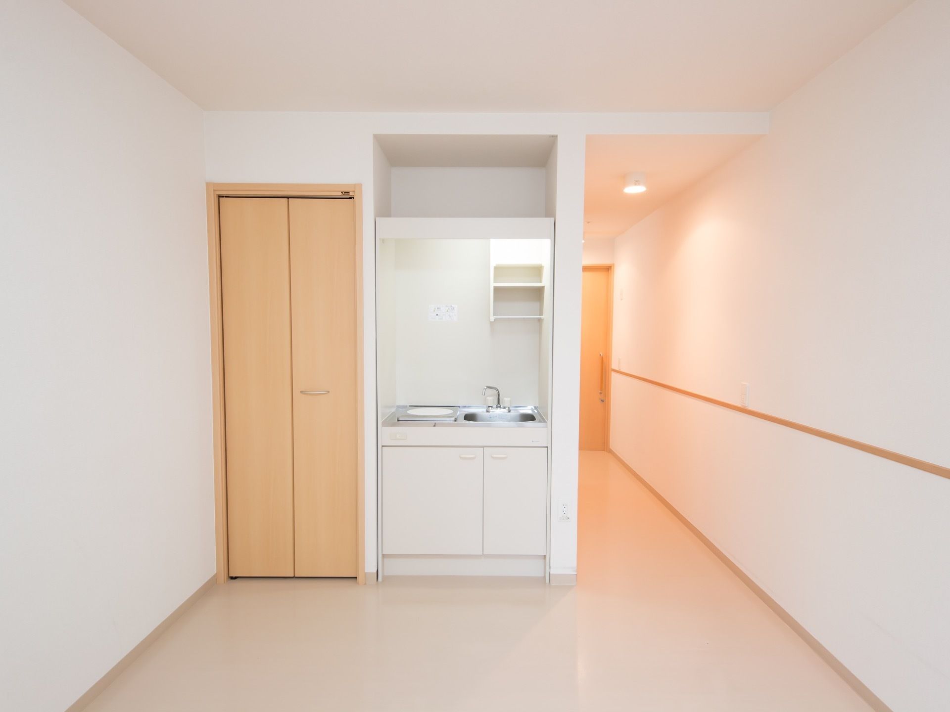 居室内に小型のキッチンがあり、その横に細長いクローゼットがある。キッチンの右側は廊下で入口の扉へ続いている。