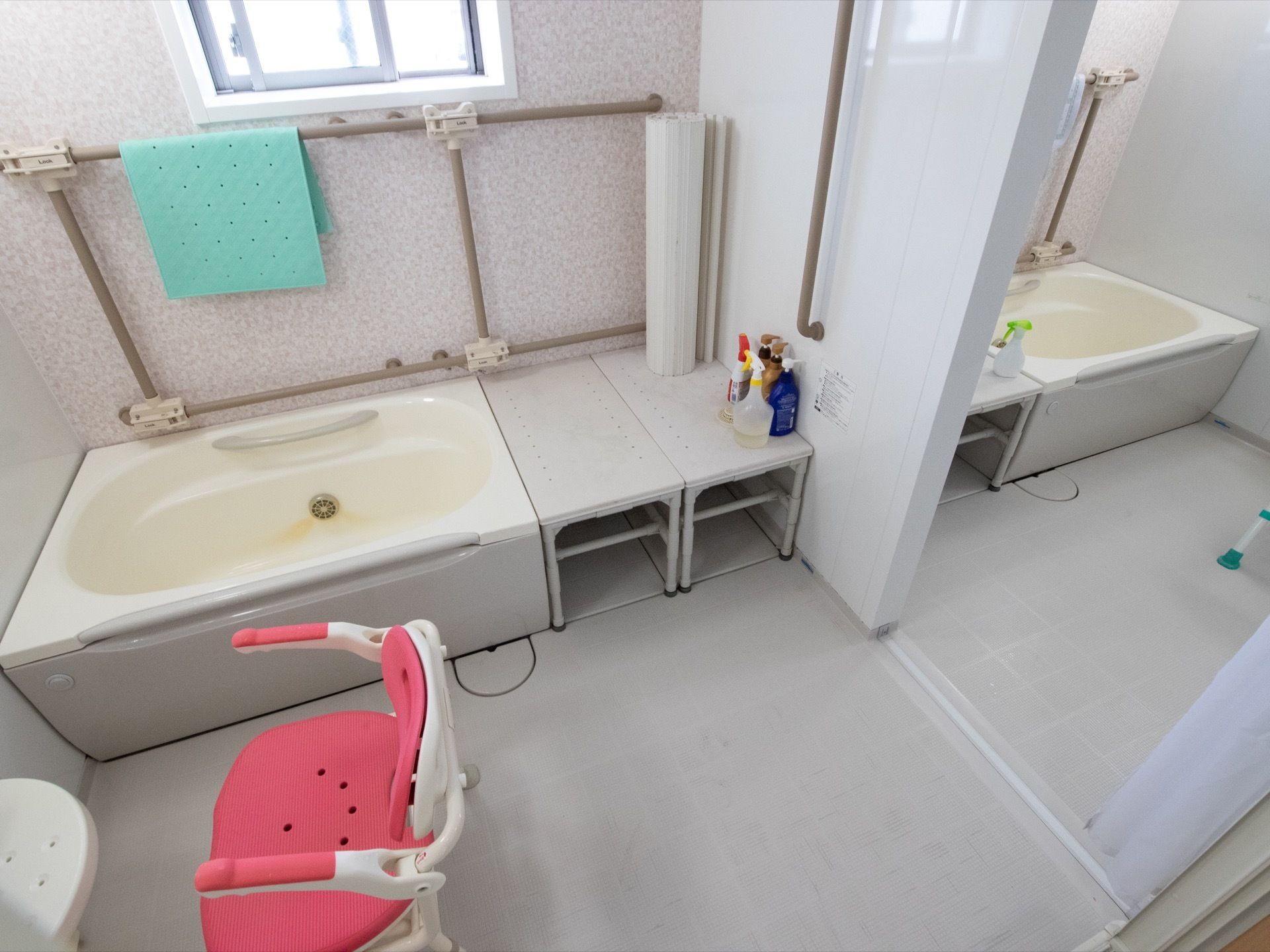 浴室が２つ並んでおり、中央に仕切りの扉が設置されている。高さのあるシャワーチェアが洗い場に置かれている。