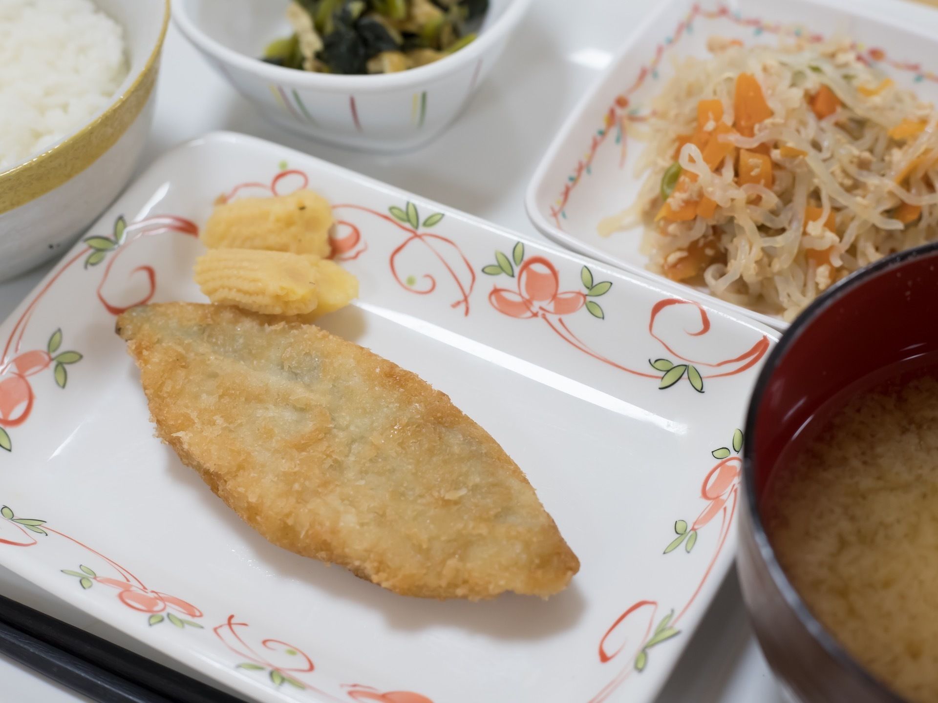 栄養面や彩りに考慮した食事である。白身魚のフライを主菜として、副菜が２品、ご飯と味噌汁が盛りつけられている。