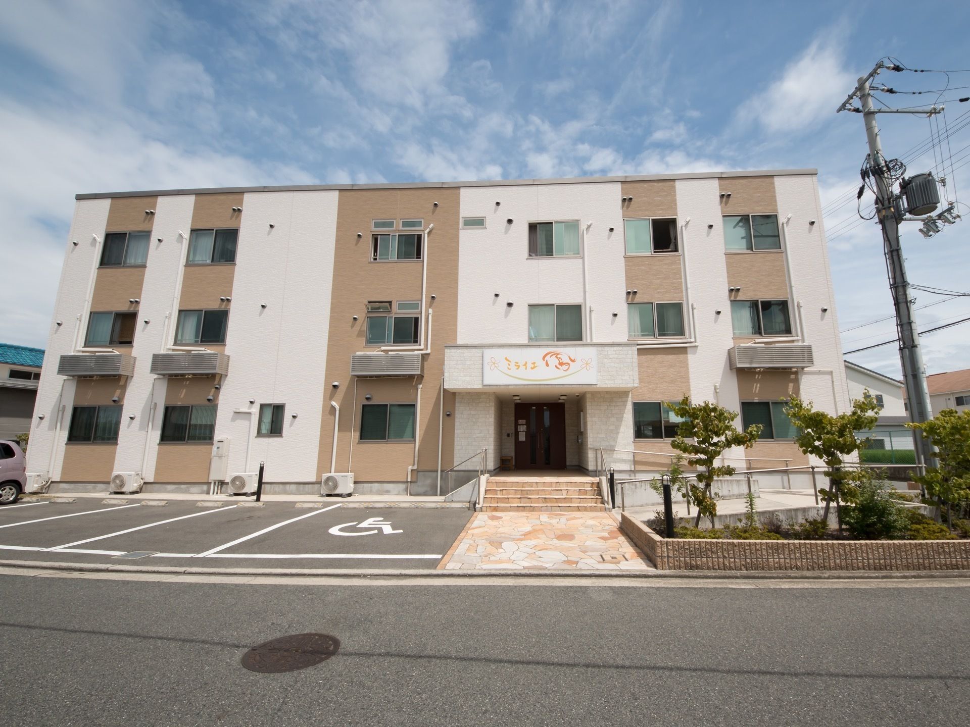 駐車場から玄関までスロープと階段が設けられた施設外観
