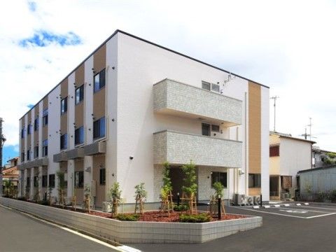 住宅地の中に馴染むように立っている施設建物と周囲の花壇の様子