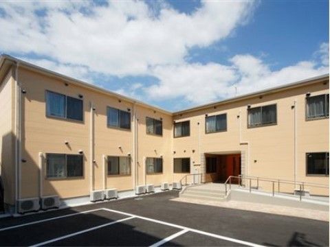 ベージュの壁で、シンプルな印象の2階建ての施設外観