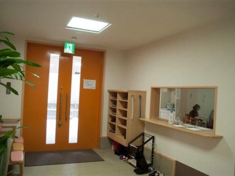 大きな両開きのドアと段差のない玄関、下駄箱と受付ホール
