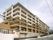 ベージュと白のおしゃれなマンション風の６階建ての建物。一階部分はヨーロッパ建築のような、アーチ構造になっている。