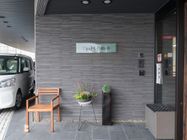 施設の玄関。施設名の看板とインターホンが壁に設置されている。屋根になる部分があり、玄関に車を横付けすることが可能。