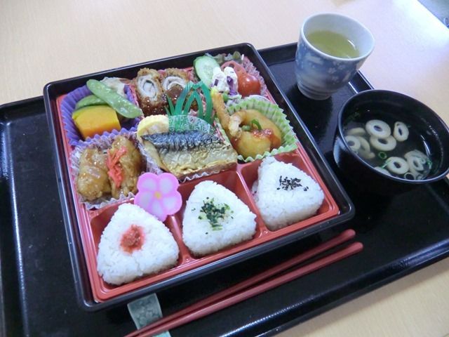 三色のおにぎりと、天ぷらや焼き魚、野菜の煮物やサラダが付いたメニュー