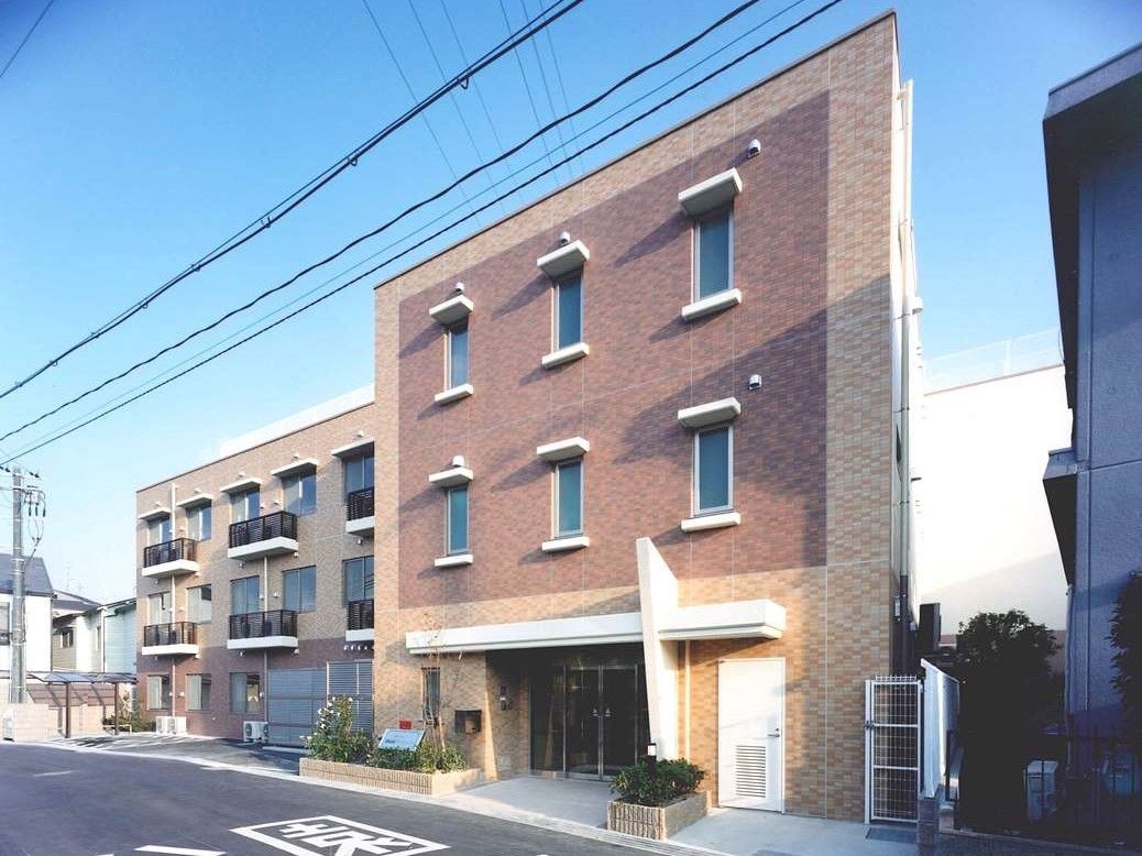 ソラスト守口の外観。斜めにカットされたような屋根が特徴の施設外観。外壁はピンクと茶色でとてもおしゃれな雰囲気。