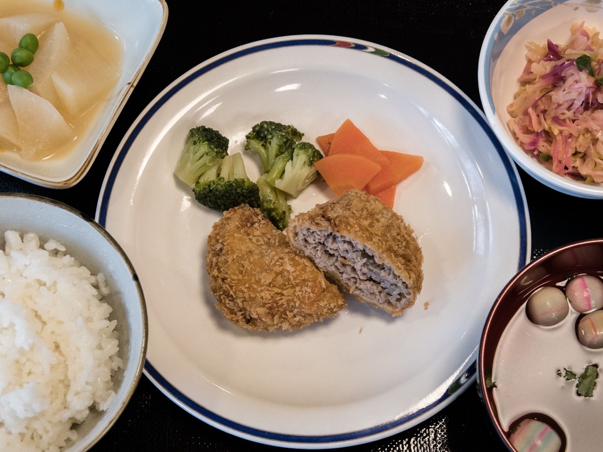 一汁三菜の食事例である。主食になるおかずは肉が使用され、ボリューム感がある。器にも気を配り、目でも楽しめる献立になっている。