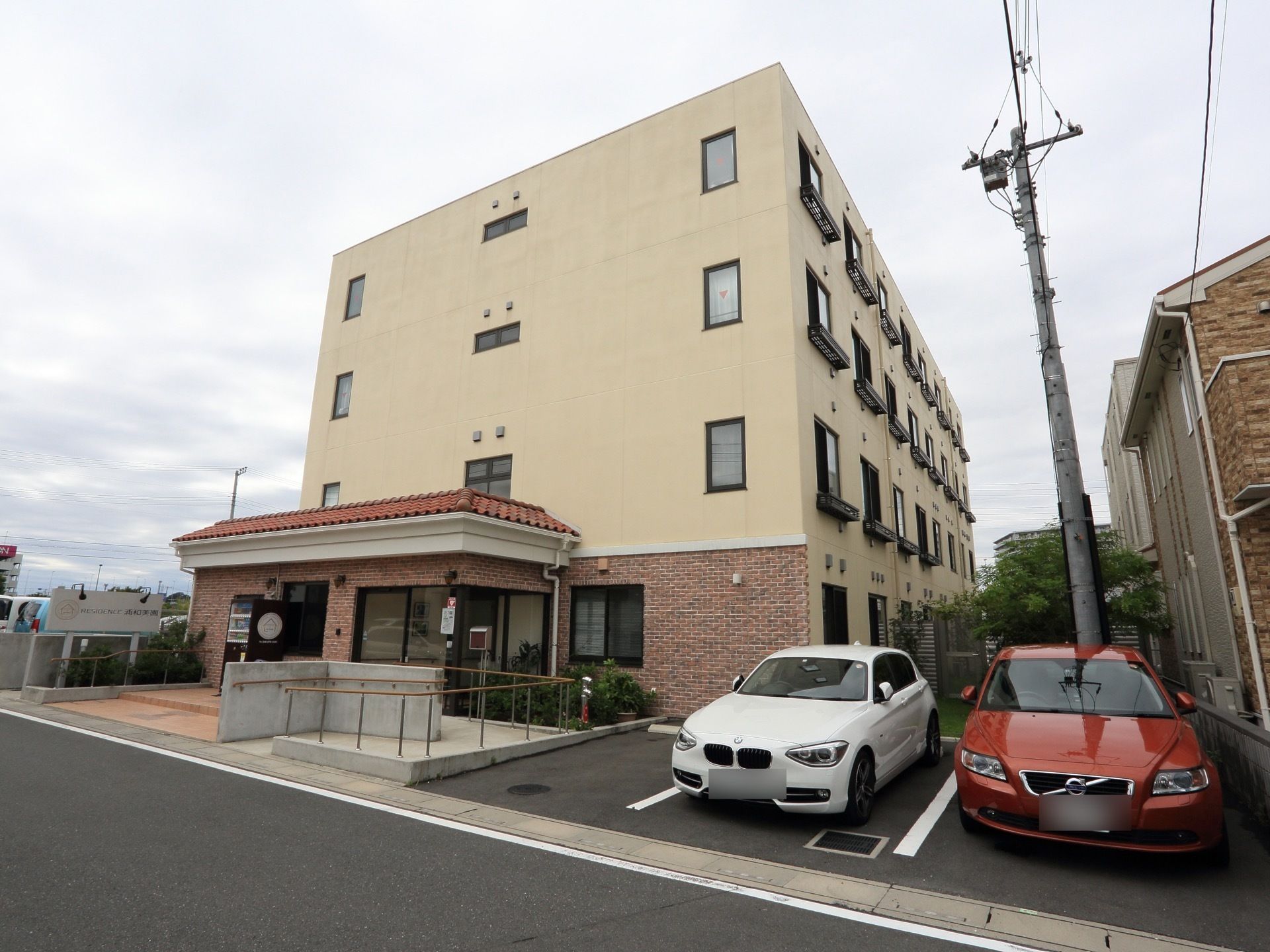 施設は４階建ての建物。道路から施設までは手すり付きのアプローチが設置されている。駐車場は３台分完備している。