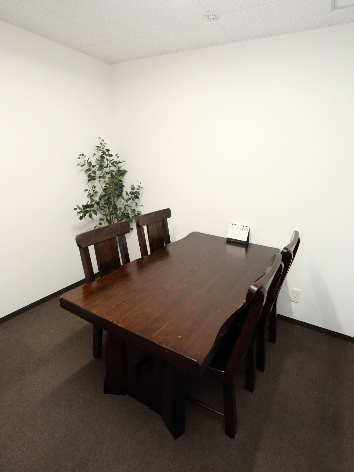 相談室のフロアはカーペット敷き。部屋はダークブラウンと白で統一され、落ち着いた雰囲気になっている。観葉植物も置かれている。