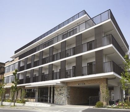 白色の壁を基調とした建物に、黒色の柵が設置されているシックな色合いの施設外観