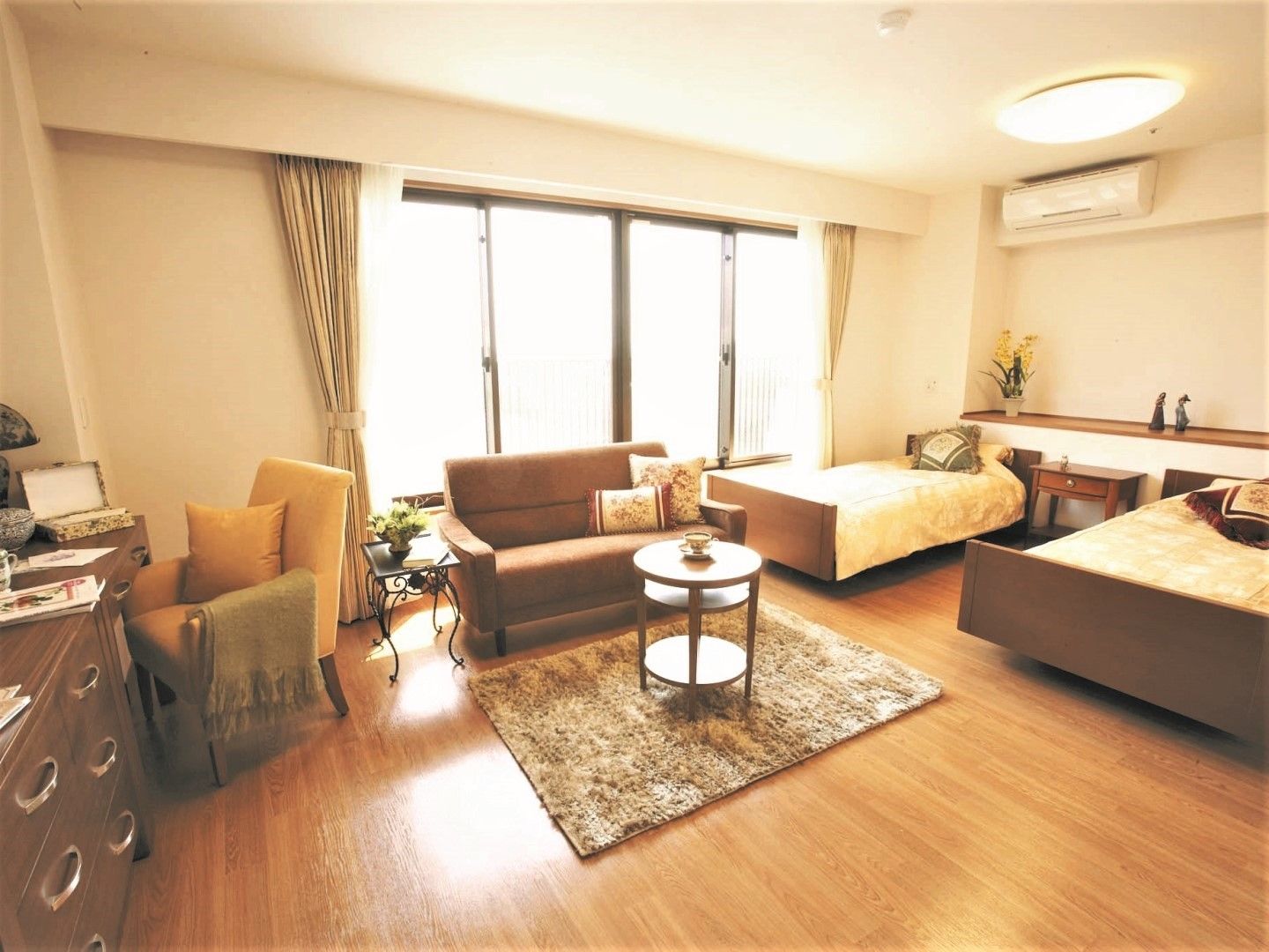 茶色く小さいソファとテーブルが置かれた部屋。窓際にはベッドが2台置かれている