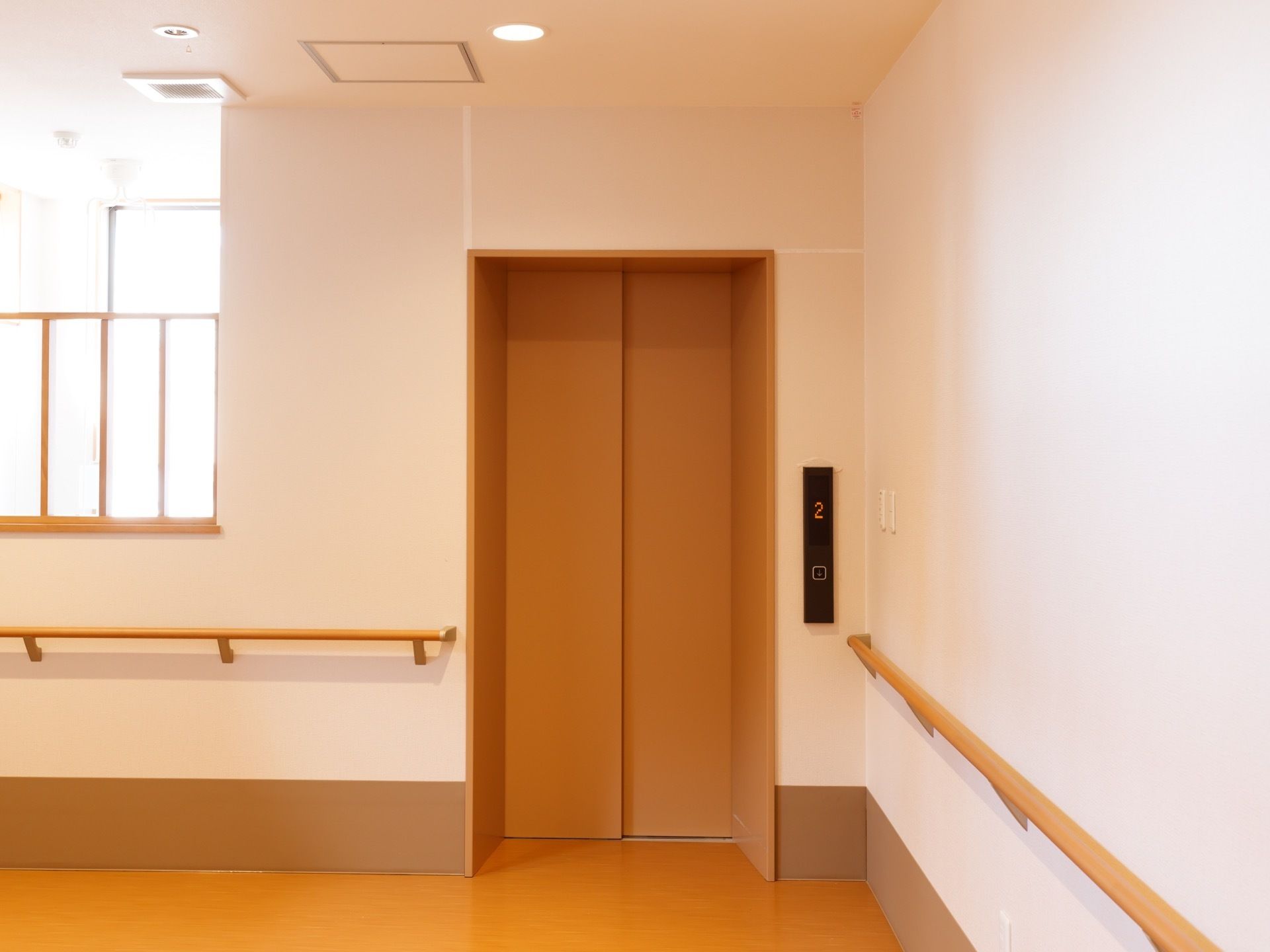 白と茶色で室内が統一されている。エレベーターの前は広くなっている。壁全体に手すりが設置されている。ボタンは車椅子でも押せる位置にある。