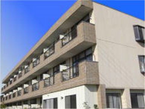 青空が美しい、ベージュ系に統一された3階建ての建物