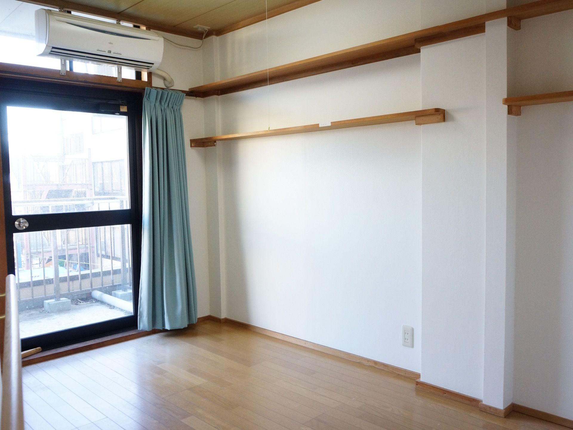 居室は大きな窓があり、明るい。窓からベランダに出ることができる。壁の上部には木製の棚が複数取り付けられている。