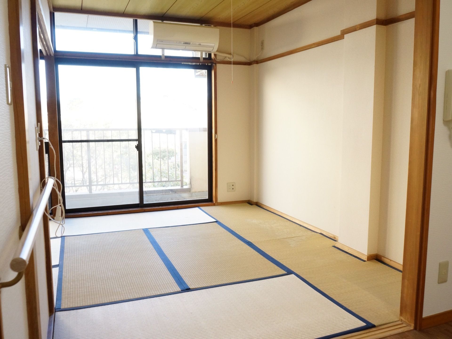 畳が敷かれた６畳の和室。窓からベランダに出れる。窓の上部にはエアコンが取り付けられている。壁にはナースコールが付いている。