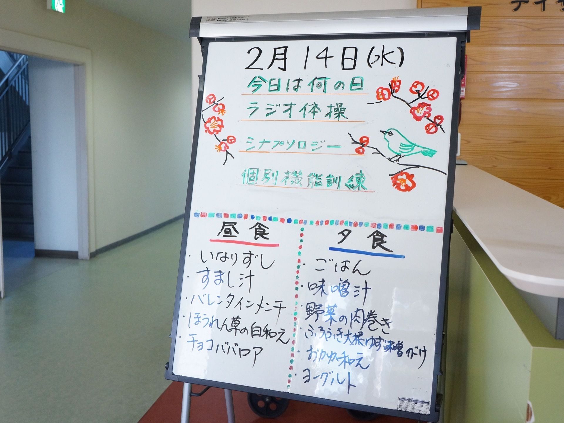 大型のホワイトボードが置かれ、スタッフが手書きで一日の予定や、その日の昼食と夕食の献立を記入している。