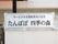 館外に施設名の看板が取り付けられている。看板は白く、字は黒。隅にはシルバーの縁がある。4隅には白のカバーが付けられている。