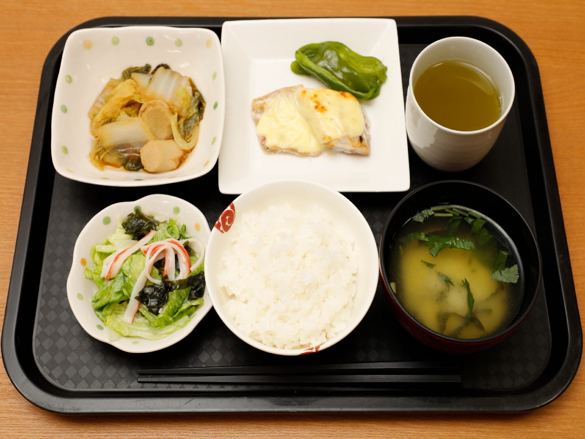 一汁三菜のバランスの良い食事が、トレーに並べて提供されている。レタスのサラダ、白菜の煮物など野菜中心のメニューである。