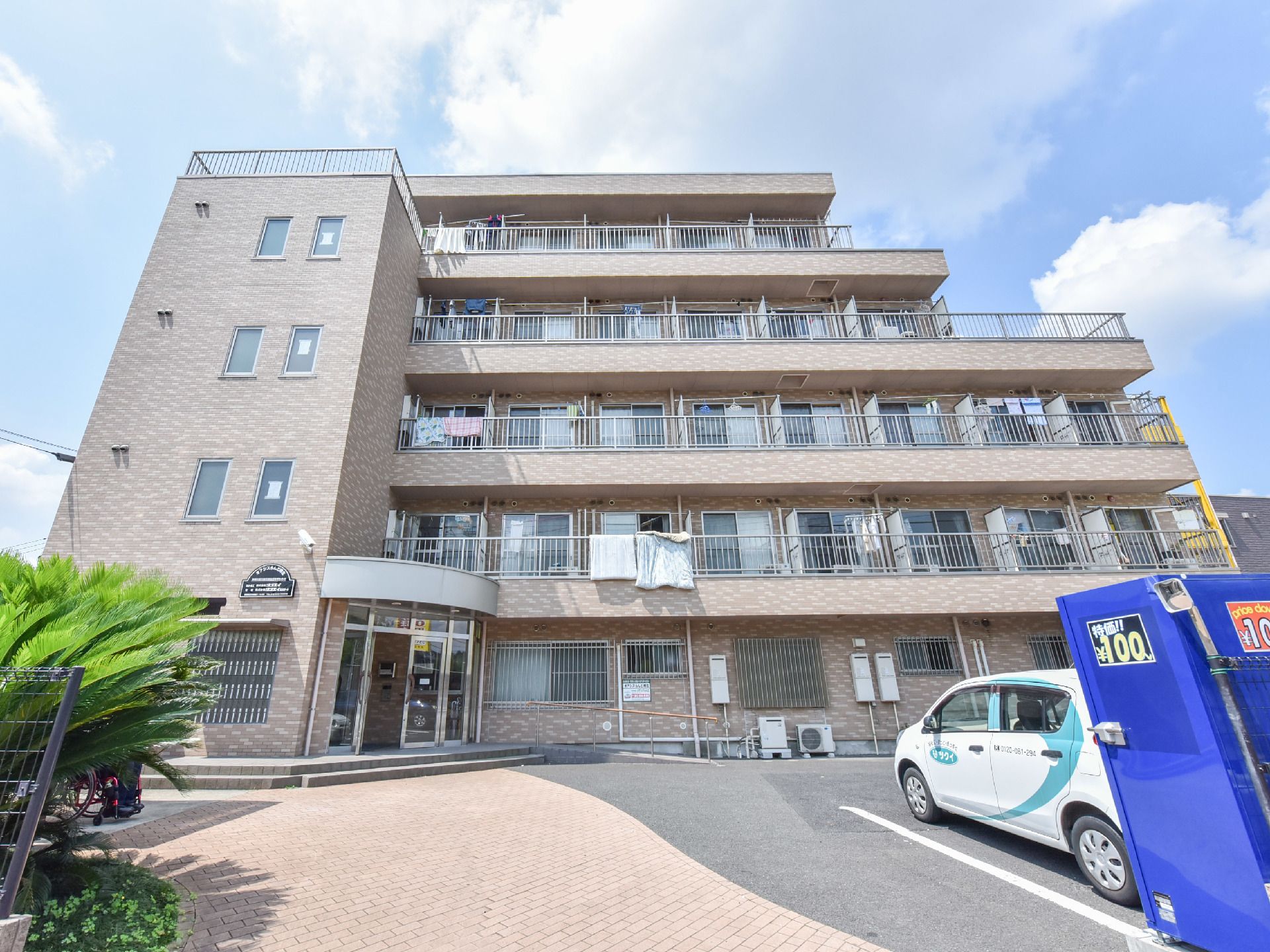 施設建物を正面アングルから見たところ。アパートのような5階建ての構造をしていて、布団が干されているベランダがある。