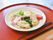 タレのかかったうどんが赤いお盆に乗っている。ゆで卵やわかめにハムにトマトなども加えられ栄養バランスが考えられている。