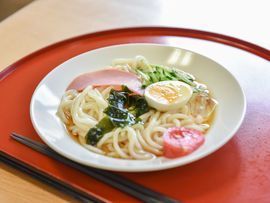 施設では栄養バランスに配慮されて食事が用意されている。うどんにはわかめやトマト、ゆで卵などが追加される。