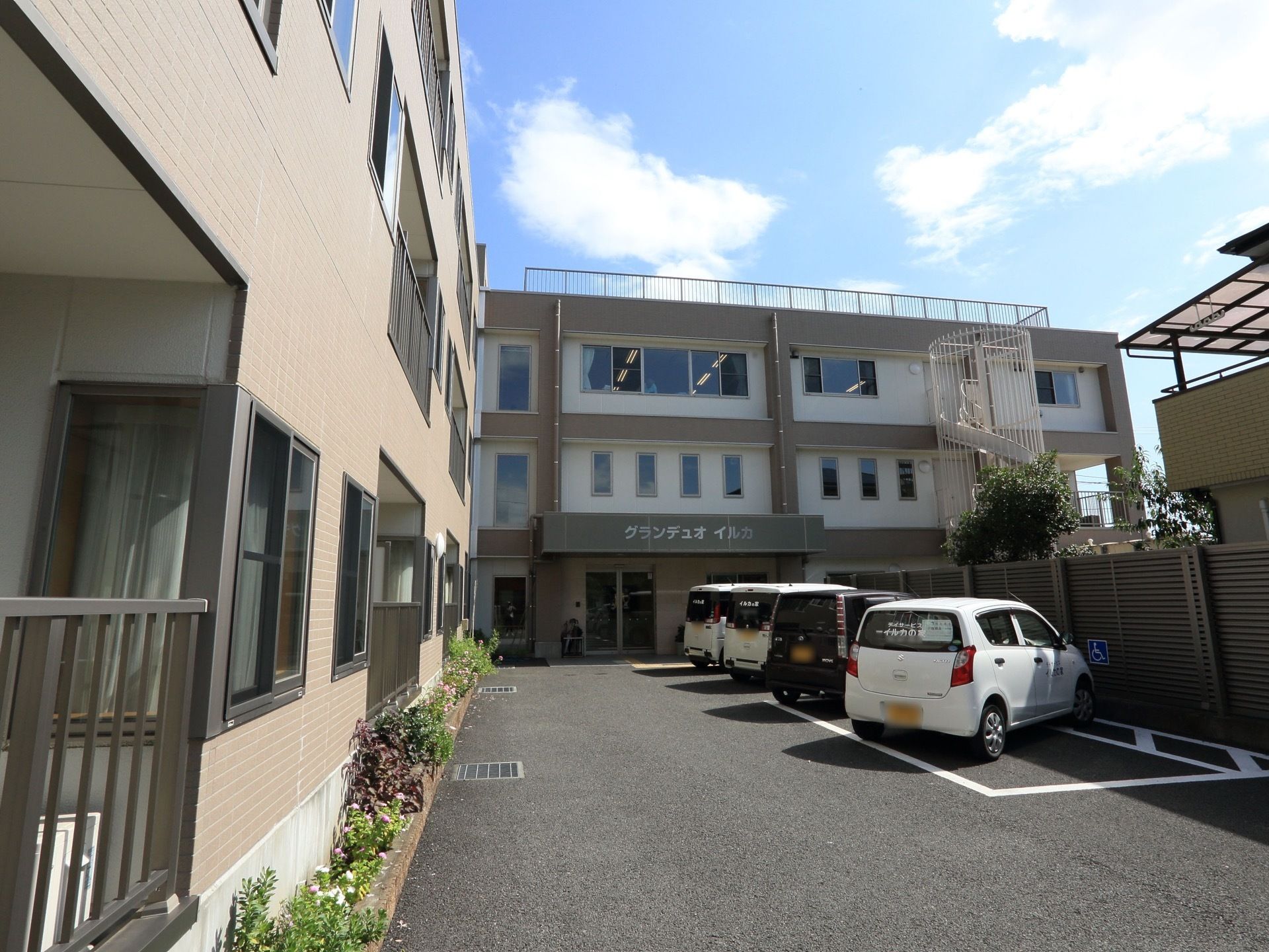 施設敷地内にある駐車場である。施設専用車や乗用車が停車している。遠方のご家族様もお越しいただきやすい。