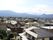 施設から見える景色である。大空に緑濃い山々の連なりが奥に見え、麓からこちらに向かって住宅地の広がりが見える。