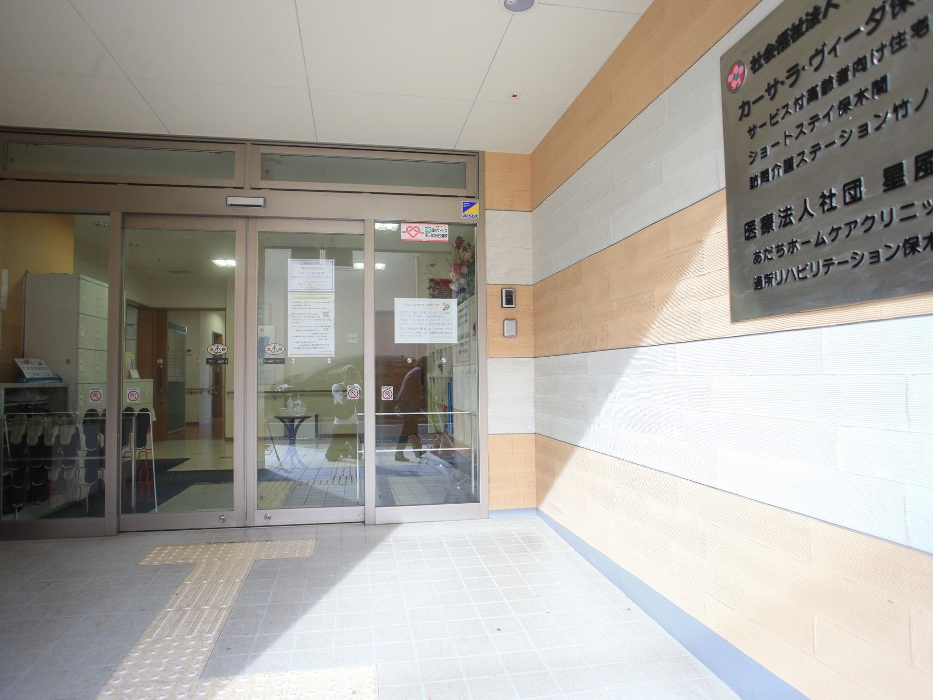 玄関前は広々としており、ガラス張り自動ドアが取りつけられている。右側の壁には、施設の簡単な概要と名称が書かれている。