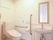 ゆったりとした広さの室内には、タンク付きのトイレと洗面台が設置されている。壁には、てすりと鏡が取りつけられている。