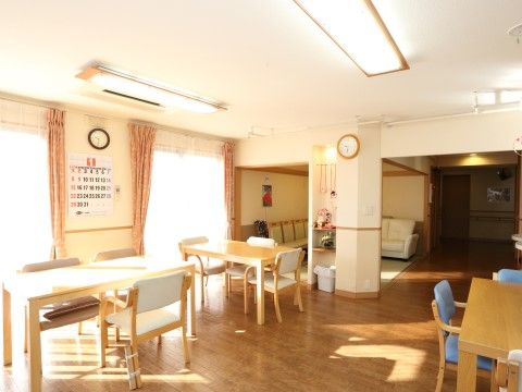 「グループホームいずみ別荘」食堂。壁にはカレンダーが貼り付けてあり。外からは太陽の清々しい日差しが室内を明るく照らしています。