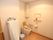 共用トイレの壁には、手すりと操作パネルが取り付けられている。便座には、背もたれとひじ掛けが設置されている。