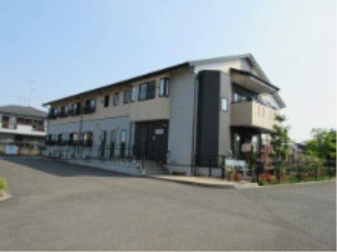 裏庭には草木が生い茂り、モノトーンカラーでシックなデザインの2階建ての建物