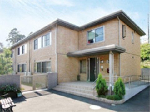 玄関前には階段と、スロープが設置された明るい色身の2階建ての施設