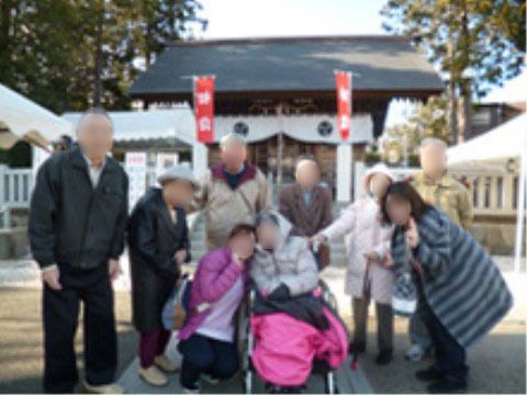 神社の前で、車椅子の方を中心に、記念写真を撮るご年配のグループ