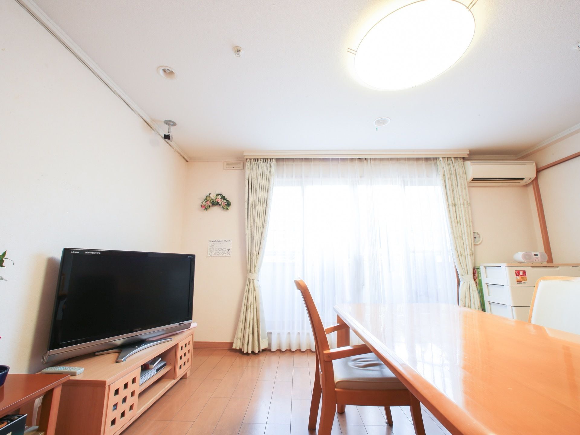 明るく広い食堂には、ダイニングテーブルやチェストが配置されている。エアコンや薄型テレビも設置されている。