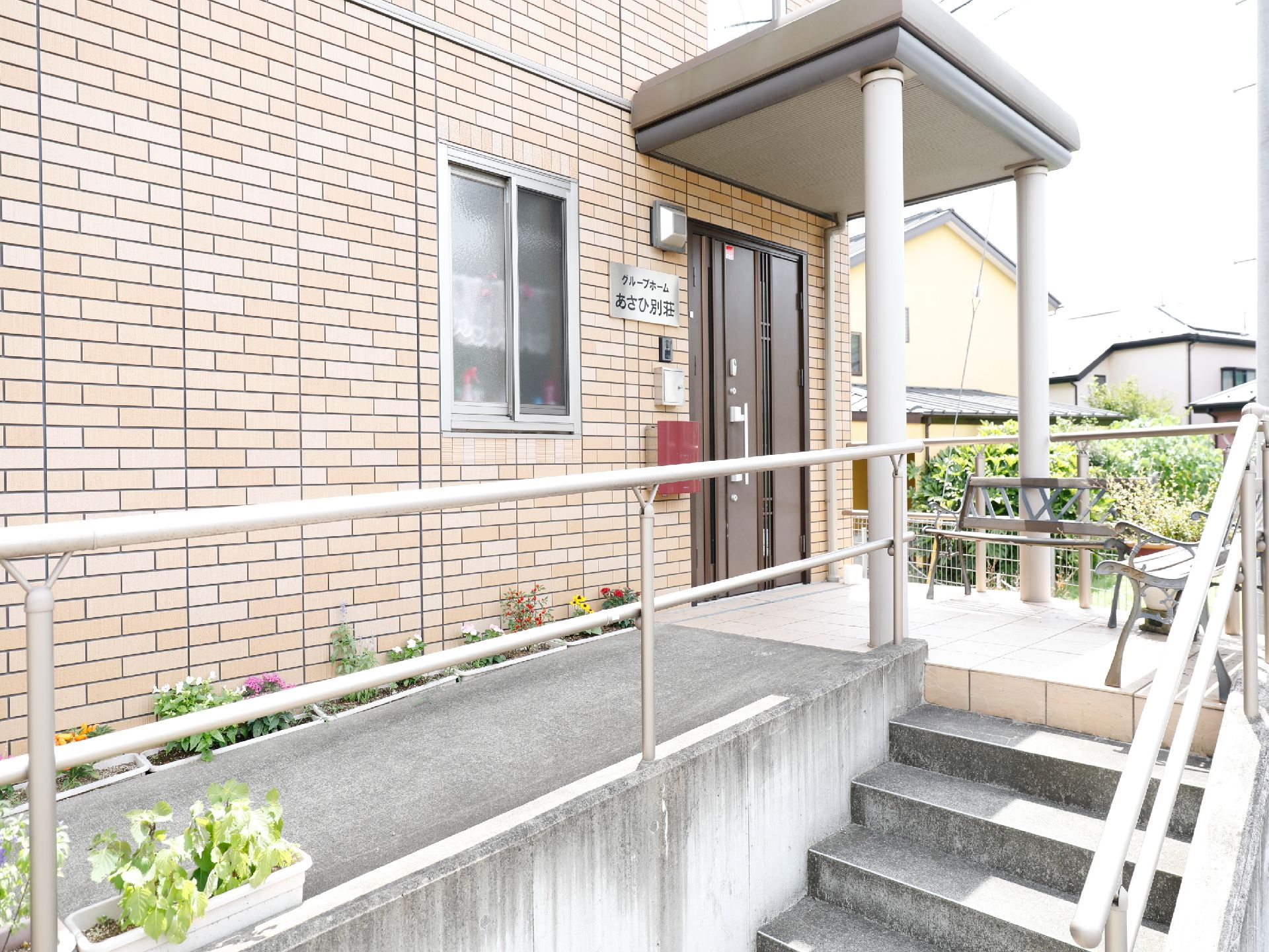 玄関出入口の建物横側にはアプローチが設置されている。また、階段スペースも設けられている。傍には手すりがある。