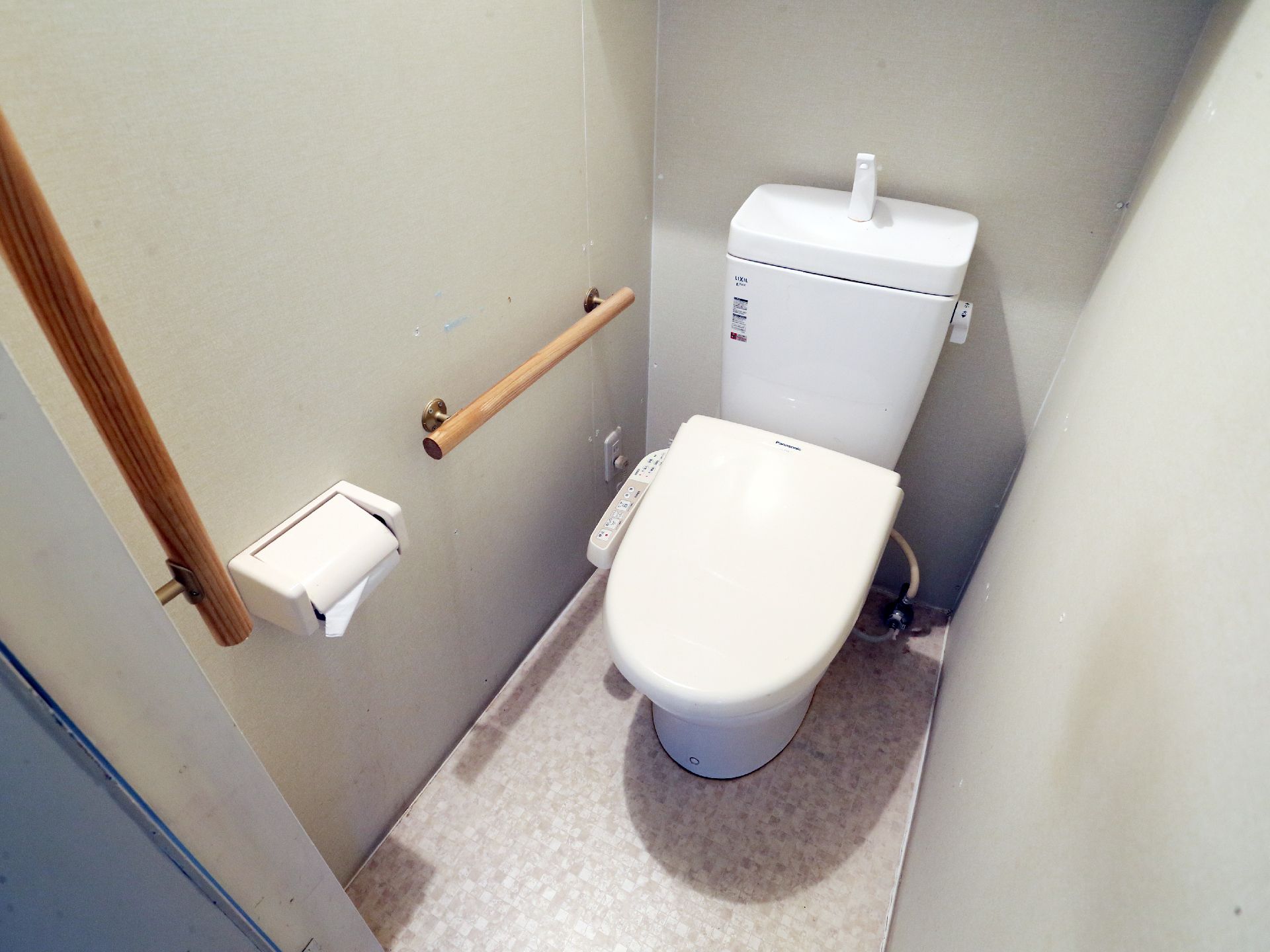 トイレの壁にはさまざまな箇所に手すりがついている。温水洗浄便座のため便利といえる。白を基調とした落ち着いた空間だ。