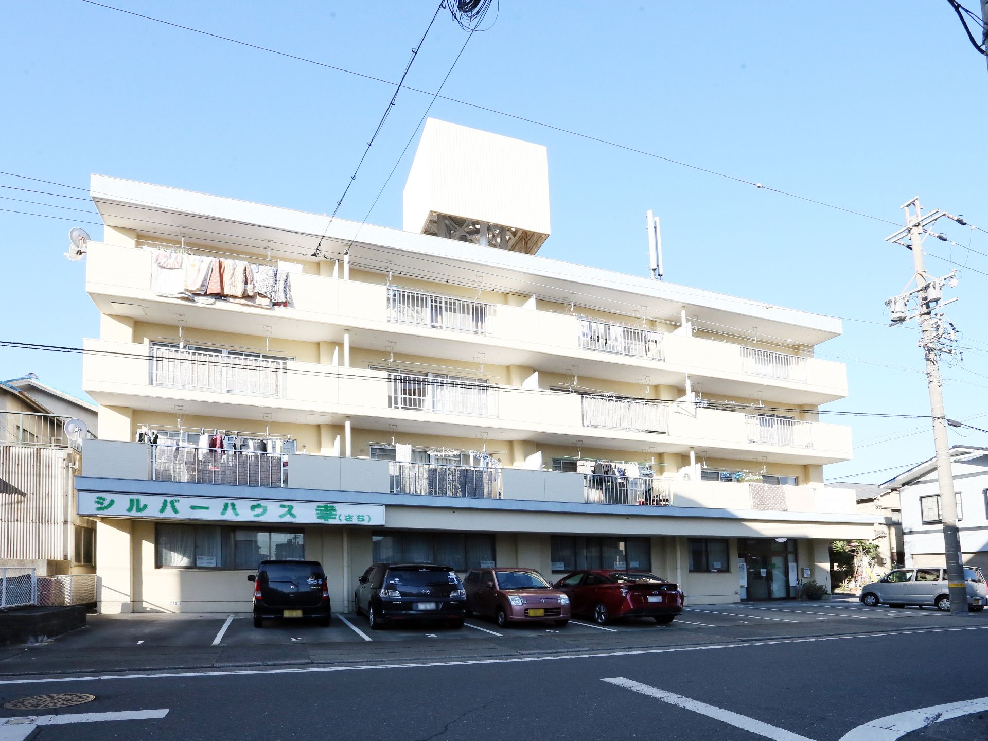 真っ白な外壁が清潔感のあり、1階には駐車スペースが設けられた4階建ての建物