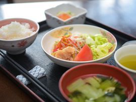 汁椀の方から接写した写真。他にご飯、小鉢、お茶などがあり、中央にはトマトや茹で野菜の入った皿が見える。